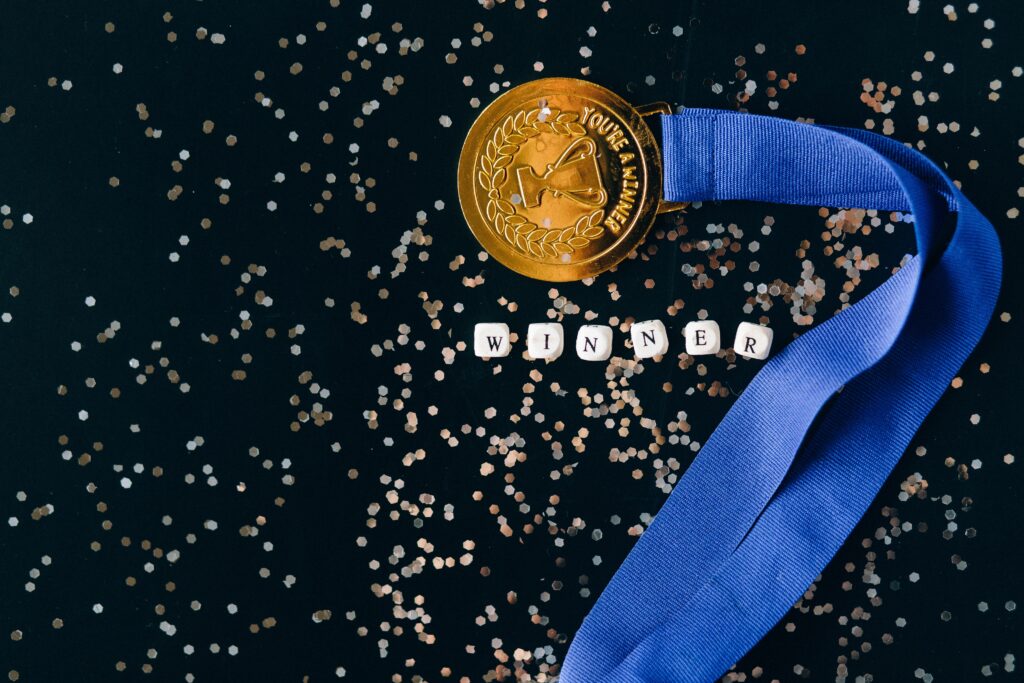 home broker: Vemos uma medalha de ouro com uma fita azul, com um troféu estampado e com os seguintes dizeres: "You're the winner", que significa "Você é o vencedor"