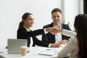 Executivos sentados em uma mesa apertam as mãos na negociação de um take over